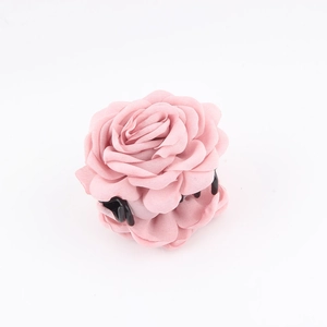 Dettaglio dei petali di tessuto rosa stratificati su un fermaglio a rosa per capelli
