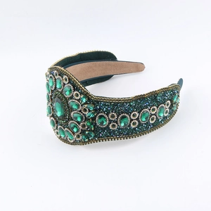 Macro detail of emerald green rhinestones and golden woven texture on luxury headband