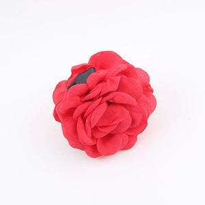 Dettaglio dei petali di rosa in tessuto rosso e della clip per capelli in metallo nero