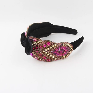 Close-up of velvet headband with pink rhinestones, purple crystals and gold studs