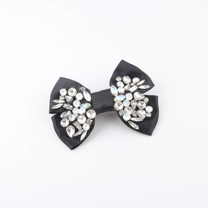 Close-up of black satin bow hair clip with luxury rhinestone embellishments in macro view