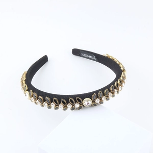 Detail of handcrafted black headband featuring leaf-shaped crystals and Hand Made label