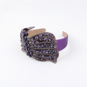 Detailed view of luxury purple headband featuring crystal wings and satin fabric