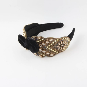 Detail of luxury velvet headband featuring gold rivets, crystals, and a large bow detail