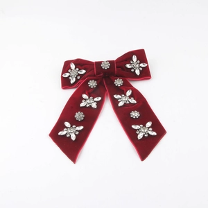 Detail of red velvet bow hair clip with sparkling rhinestones in floral patterns