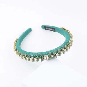 Detailed view of handmade emerald green padded headband with sparkly rhinestone leaf patterns