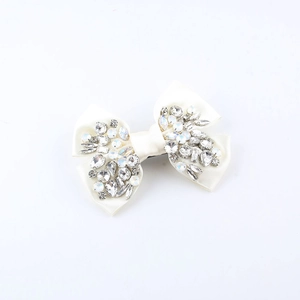 Close-up of cream satin bow hair clip with sparkling marquise and round rhinestones