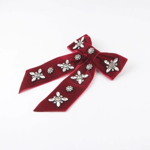 Detailed view of a red velvet bow hair clip featuring sparkling rhinestone floral patterns