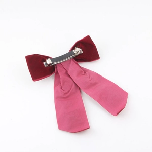 Close-up of a handmade dark red velvet bow hair clip with elegant long pink ribbons