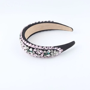 Close-up of baroque headband featuring pink and green rhinestones on black fabric base