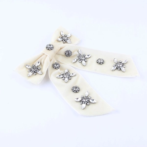 Close-up of cream velvet bow hair clip with sparkling rhinestone stars and crystals