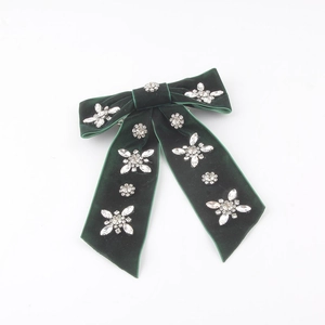 Detailed close-up of dark green velvet bow hairpin with sparkling rhinestone clusters