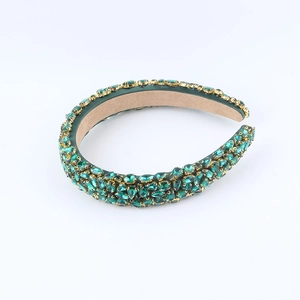 Detail of emerald green crystals in golden claw settings on a wide headband