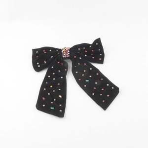 Detailed macro of black velvet bow hair clip with colorful shimmering rhinestones