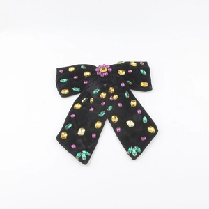Detailed macro view of black velvet bow hair clip with colorful crystal rhinestones