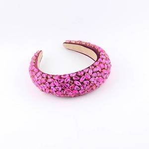 Détail d'un serre-tête rembourré en velours avec strass fuchsia et design baroque en cristal