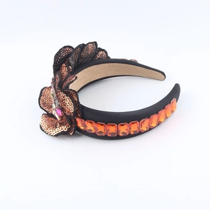 Close-up of Baroque style wide headband with bronze sequins and orange gemstone details