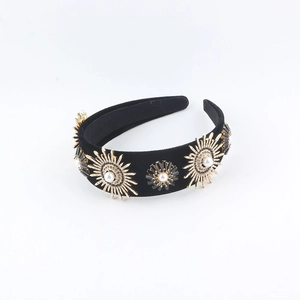Detail eines Vintage-Samt-Haarreifs mit goldenen Sonnenstrahlen und Perlen