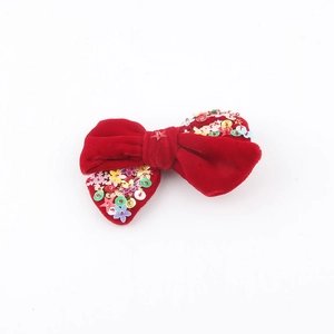 Détail d'un nœud de Noël en velours rouge avec paillettes colorées et broderie d'étoile