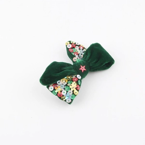 Détail d'un nœud papillon en velours vert foncé avec paillettes en forme d'étoiles et flocons