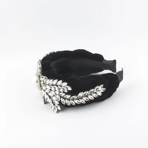 Detailed shot of black velvet headband with sparkling rhinestones and a large pearl