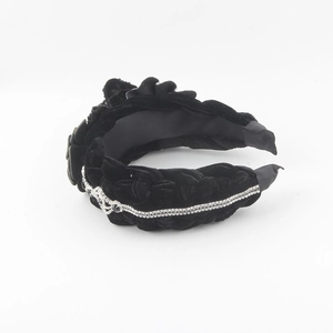 Detail of black velvet headband featuring floral applique and sparkling rhinestone accents