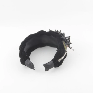 Detailed shot of a black velvet braided headband with rhinestones and beaded floral accents