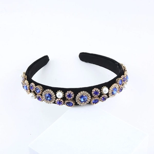 Detail of royal blue crystals and faux pearls on a black velvet wide headband