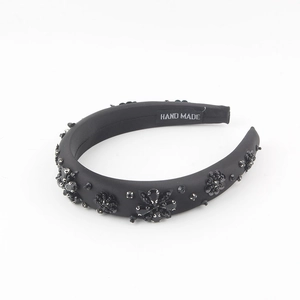 Elegant black padded headband with bead flowers and sequins on a white background