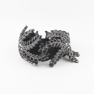 Close-up of black velvet headband with marquise rhinestones and silver leaf details