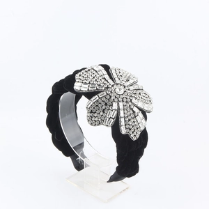 Detail view of luxury black velvet braided headband featuring a large sparkling flower rhinestone