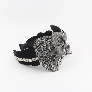 Close-up of black velvet headband with sparkling rhinestone bow and silver crystals