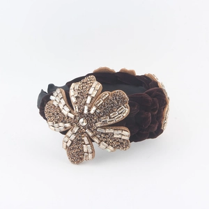 Close-up of velvet braided headband with large rhinestone encrusted flower detail
