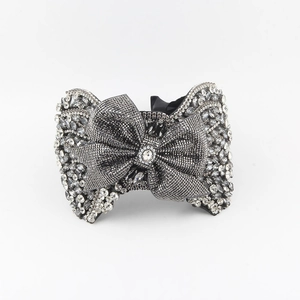 Exaggerated bow headband featuring dark grey crystals and a sparkling center diamond