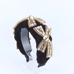 Close-up of velvet braided headband with golden rhinestone bows and pearls