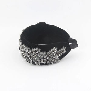 Detailed close-up of a wide black velvet headband with sparkling crystal floral embroidery