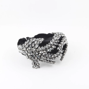 Macro detail of luxury black velvet headband with sparkling rhinestone leaf patterns