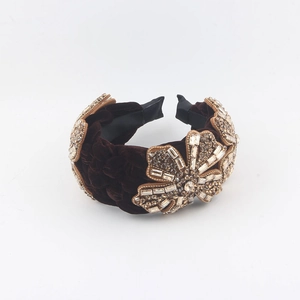 Detailed close-up of dark brown velvet headband with luxury crystal flower embellishments