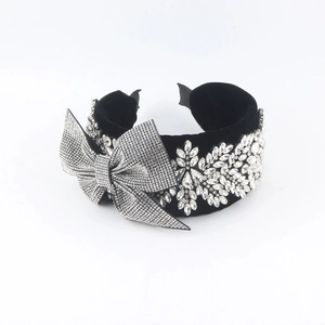 Close-up of black velvet headband with sparkling rhinestone bow and floral pattern