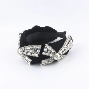 Detail of black velvet headband with sparkling rhinestone bow and white pearl accents