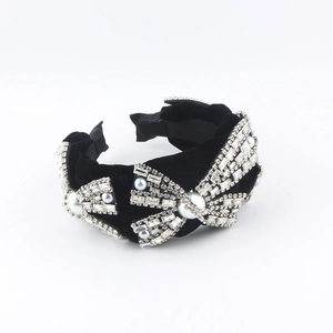 Close-up of velvet headband featuring rhinestone bow and large white pearl details