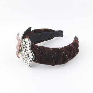 Détail d'un serre-tête en velours marron tressé avec strass brillants et décor floral