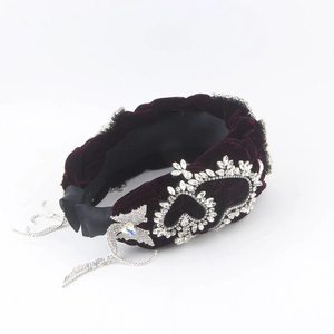 Macro detail of wine red velvet braided headband with rhinestones and tassel butterfly