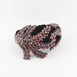 Close-up of black velvet headband featuring hand-set red crystals and rhinestone leaf pattern