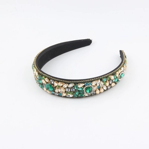 Dettaglio di un cerchietto barocco con grandi cristalli verde smeraldo e strass champagne