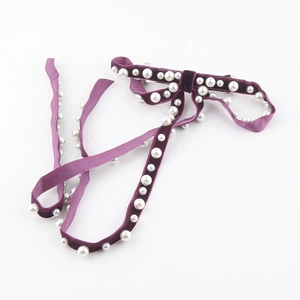 Detailed view of the purple velvet bow hair clip featuring elegant white faux pearls