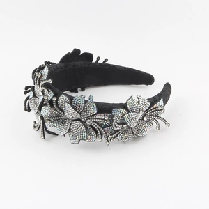Dettaglio di un cerchietto in tessuto nero con decorazioni floreali in strass lucidi