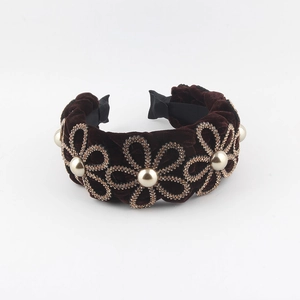 Close-up of velvet headband with golden rhinestone flowers and faux pearl accents