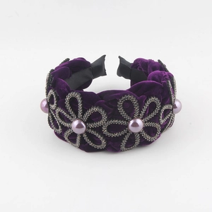 Close-up of purple velvet headband with rhinestone floral patterns and central pearl detail
