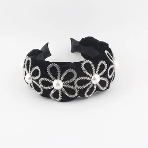 Detailed view of black velvet headband with silver rhinestone flowers and white pearls